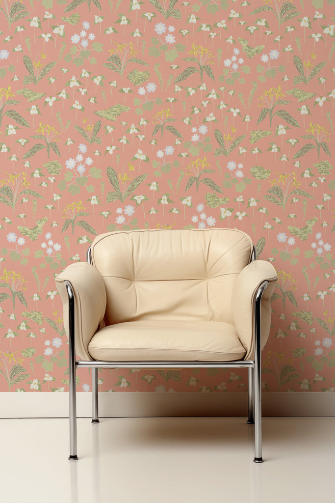 Creamy beige chair against the Forest Blooms Pink wallpaper, showcasing the first signs of spring with trilliums and trout lilies emerging on the forest floor