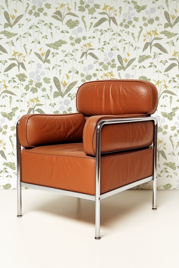 Elegant brown leather chair against the Forest Blooms White wallpaper, depicting fresh spring foliage and blossoms creating a tranquil indoor space