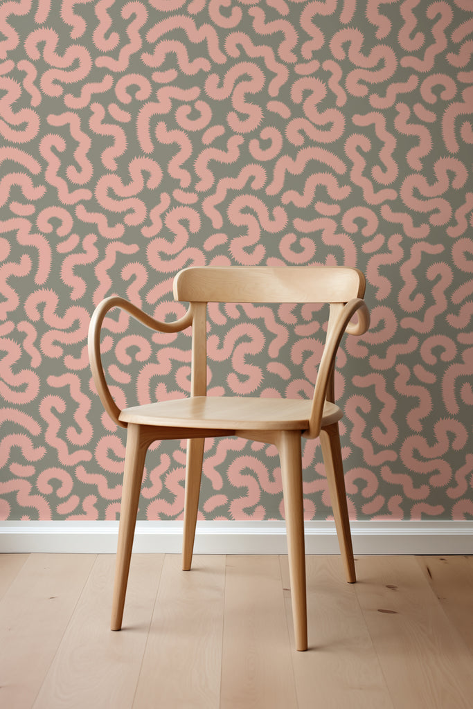 Modern curved wooden chair set against the backdrop of Kate Golding's Spring Pop Pink and Khaki wallpaper, showcasing contemporary elegance.