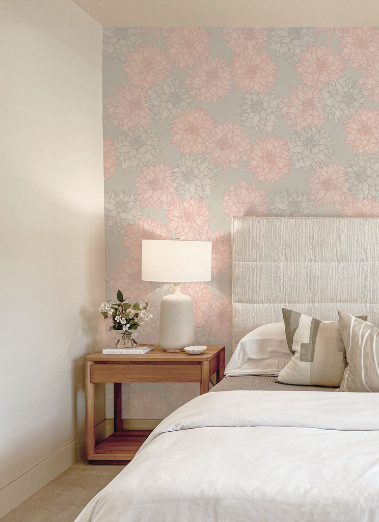 Dahlia Belle Magic Wallpaper in soft pink and grey tones adds a floral elegance to a modern bedroom with neutral decor and wood accents.
